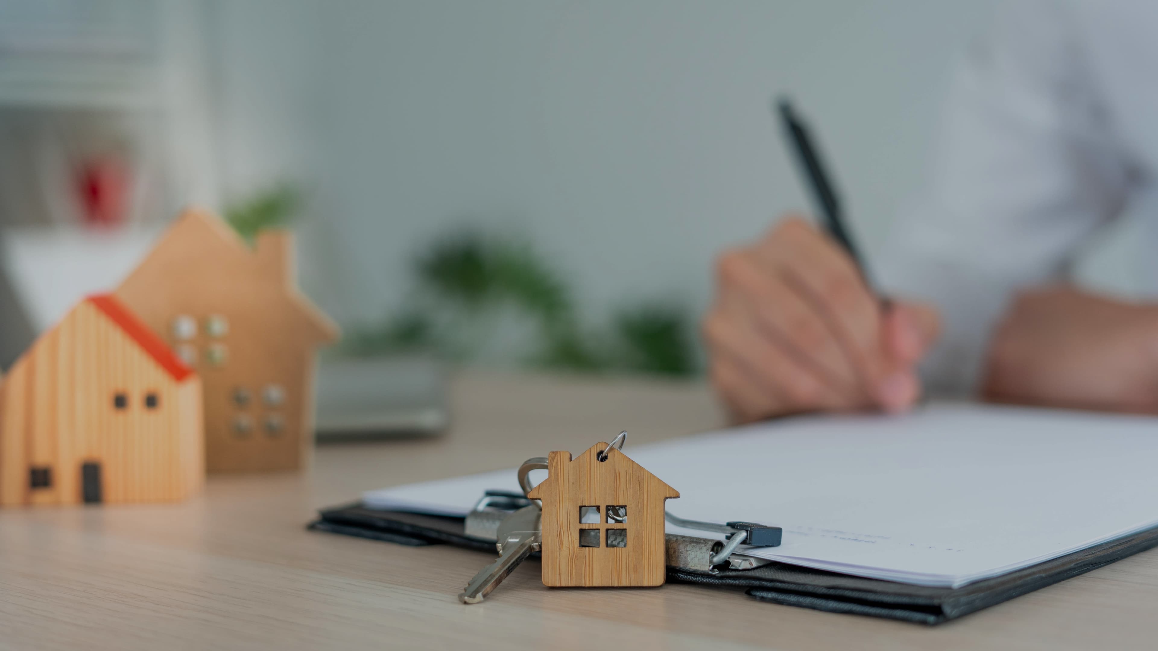 House keys and model homes beside a property agreement being signed